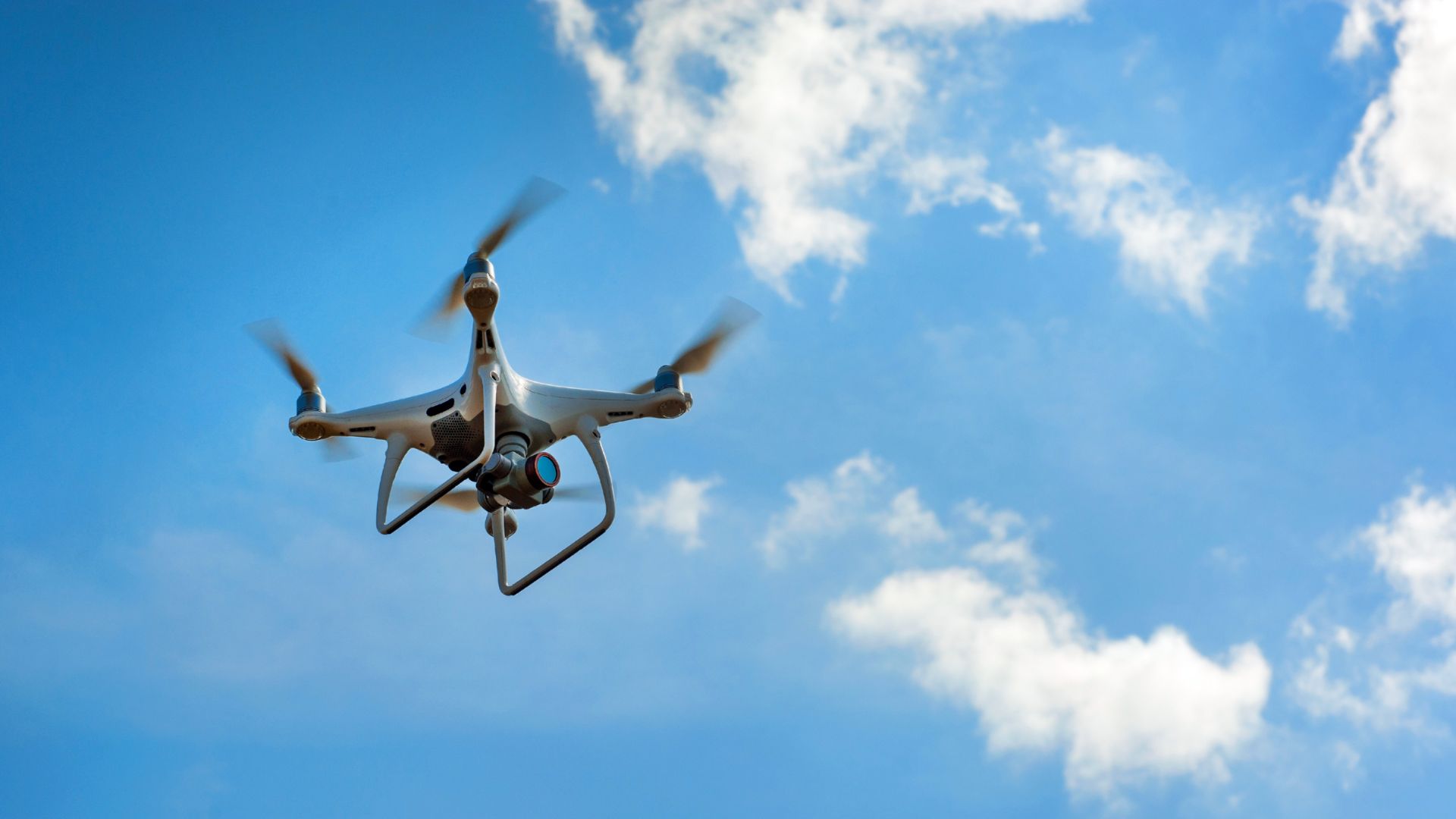 A drone flying in the sky with clouds in the background